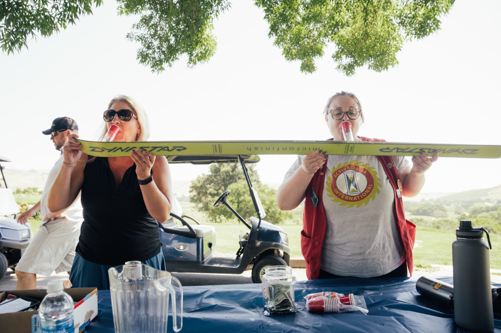 Two women playfully hoisting beam overhead together