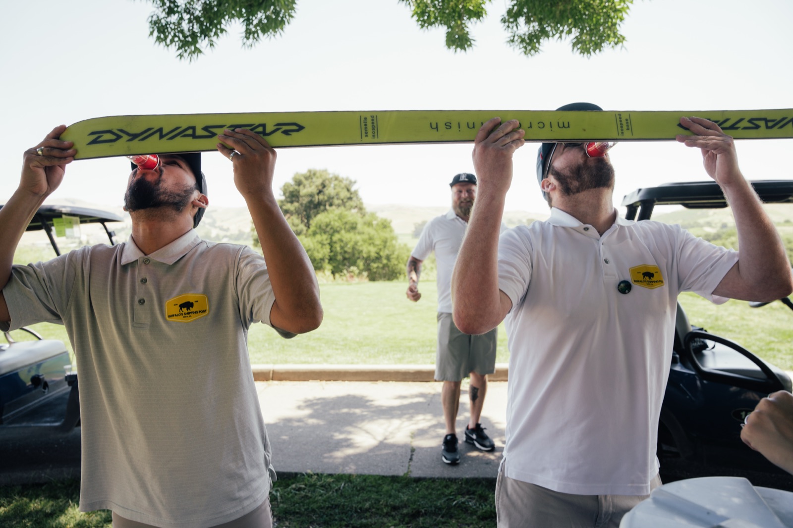 Group of men playfully holding beam overhead together