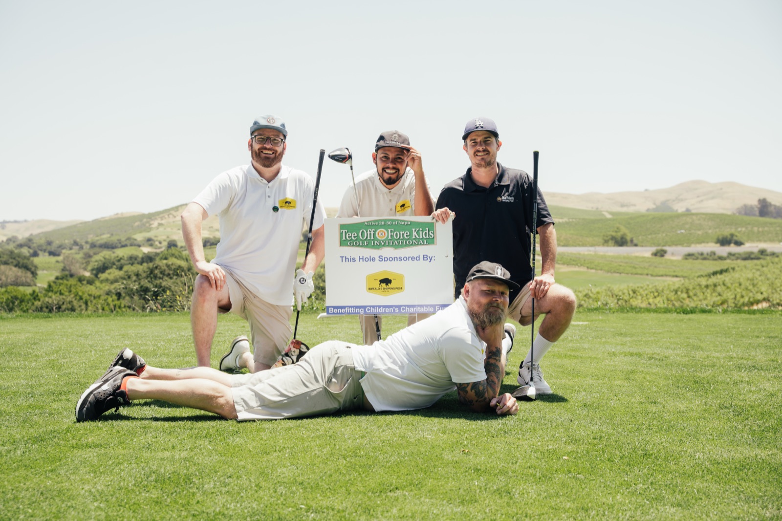 Five golfers posing together with Tee Off Fore Kids signage at sponsored hole