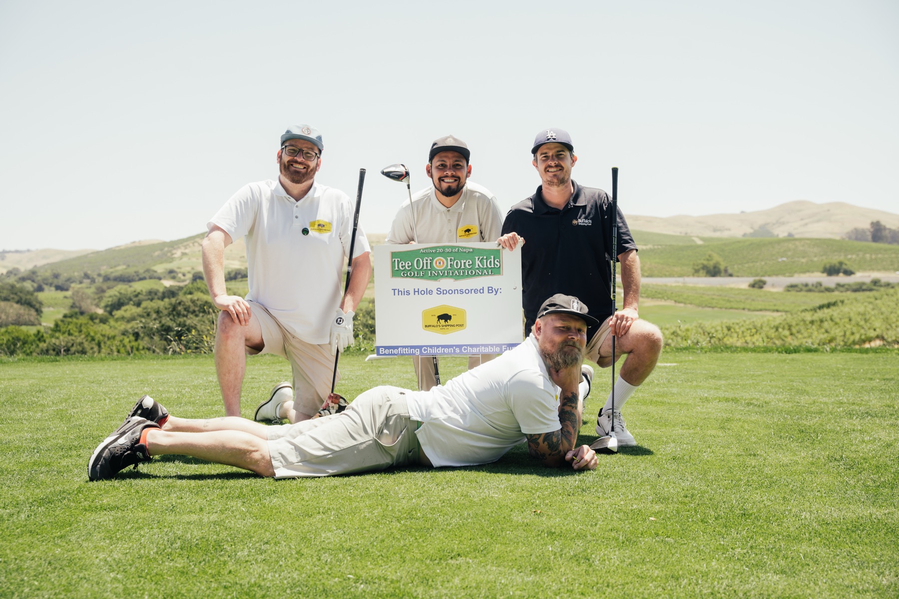 Members and friends pose with the Tee Off Fore Kids hole-sponsor sign at Chardonnay Golf Club