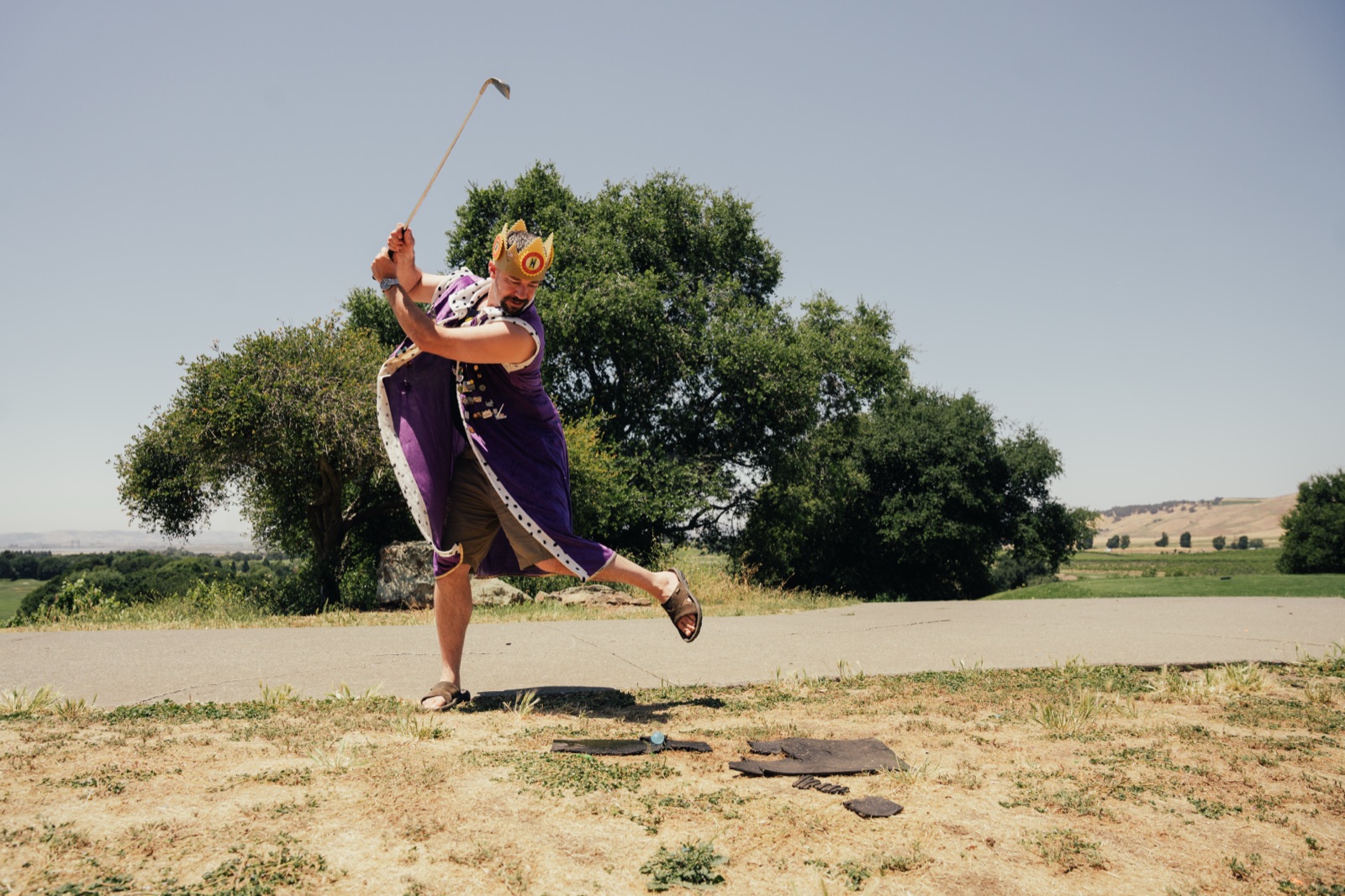 Golfer's complete swing follow-through on open field with scenic background