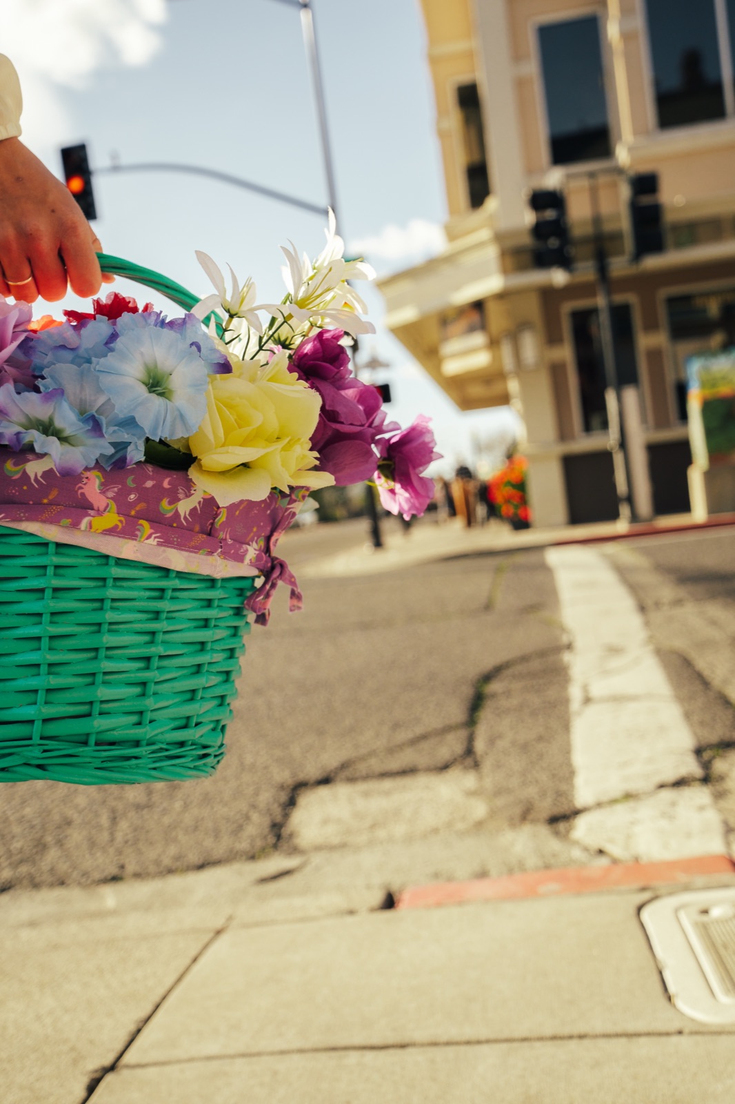 Decorated green Easter basket with colorful flowers being held on city street