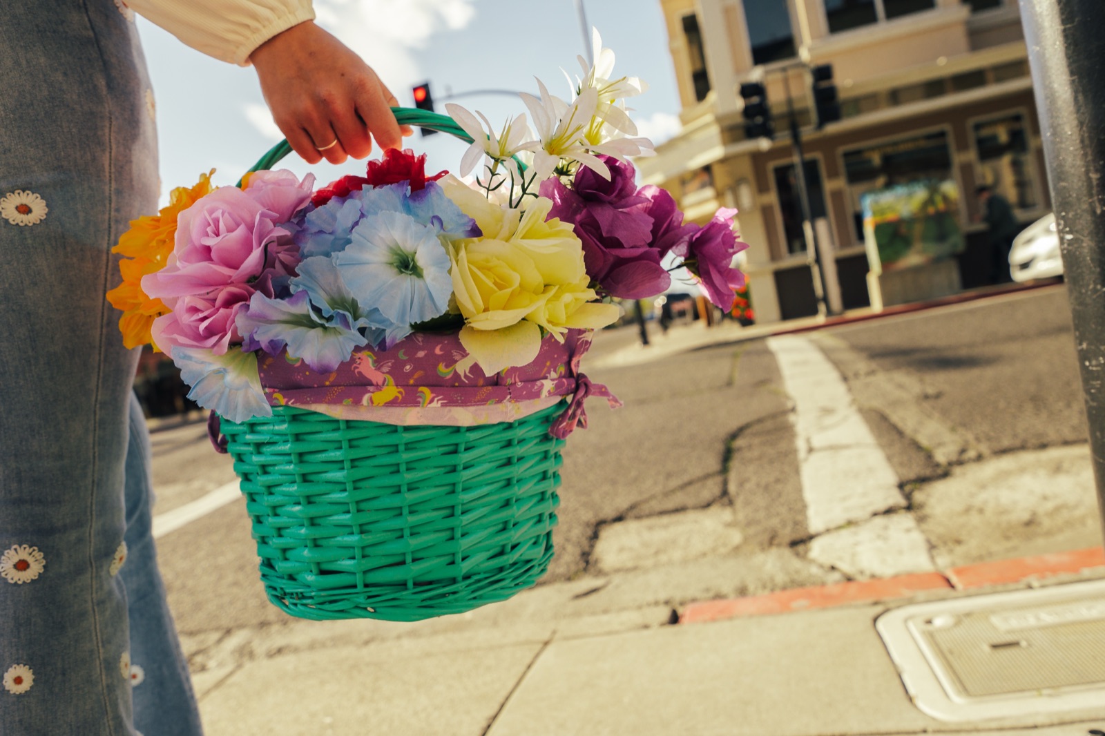 Person holding decorated Easter basket with pink, yellow, and purple flowers