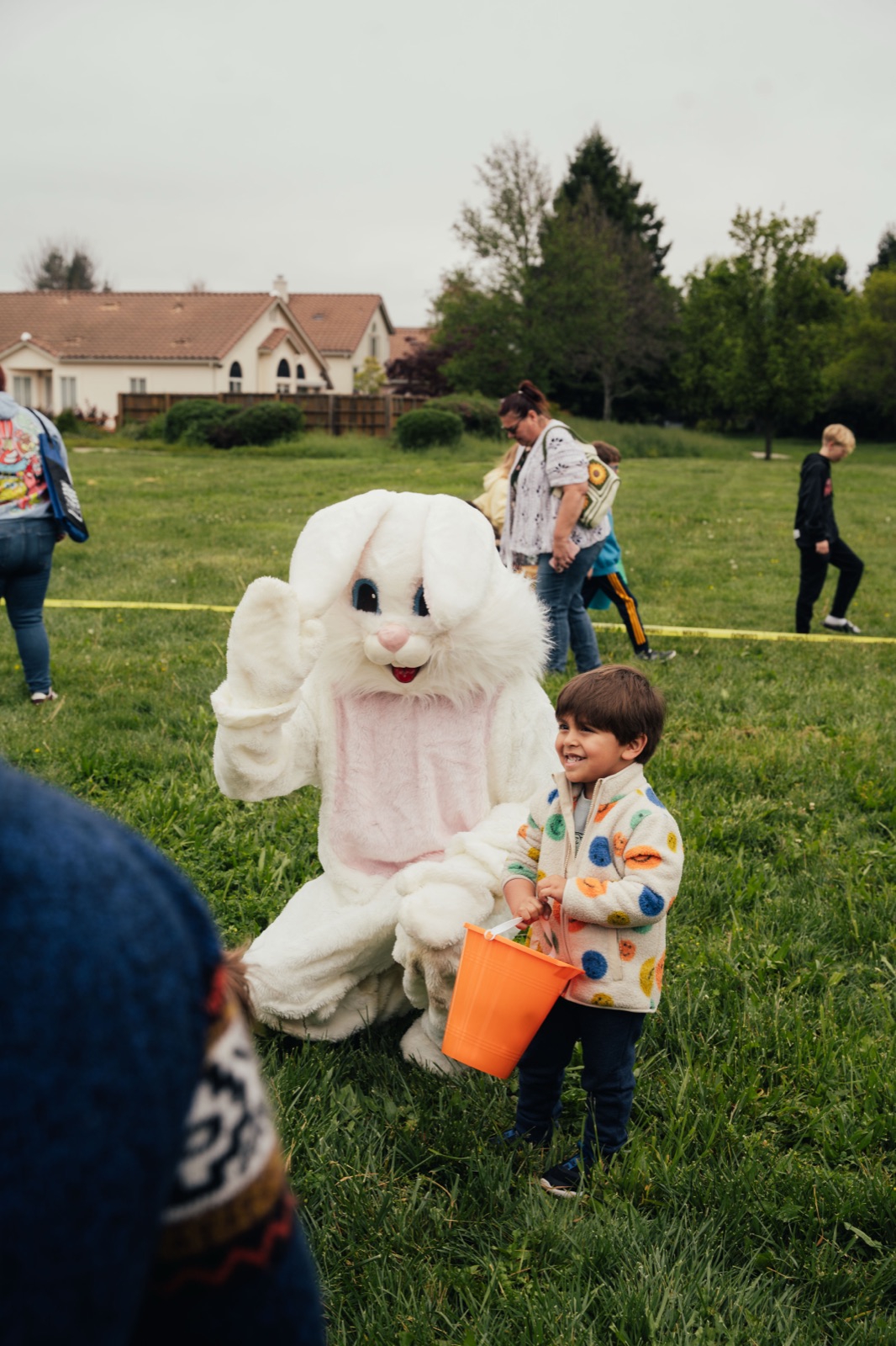 Young child in colorful tie-dye shirt posing with white Easter bunny mascot